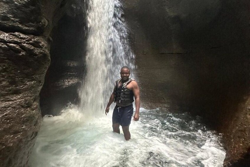 A person standing in a cave with a waterfall. 4