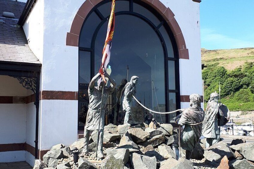 A building with a large arched entrance, statues of figures, and a flag. 2