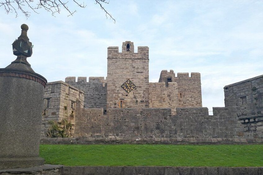 A historic stone castle with a central tower, surrounded by a well-maintained lawn. 2