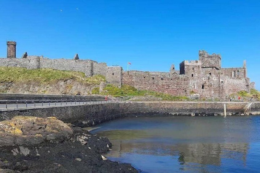 A historic stone castle by a calm body of water. 3