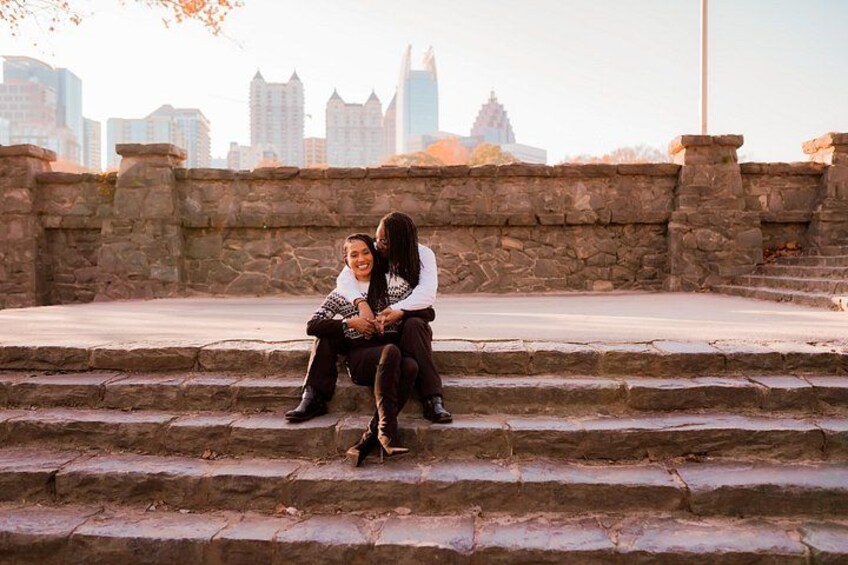 Una pareja sentada en escalones de piedra con un horizonte urbano al fondo. 3