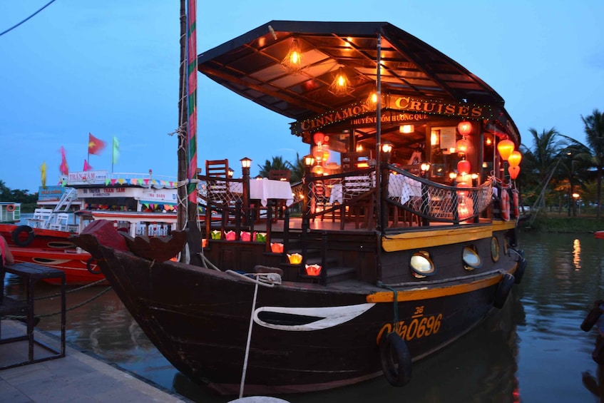 A boat with a covered dining area named "CINNAMON CRUISES" docked at a pier. 1