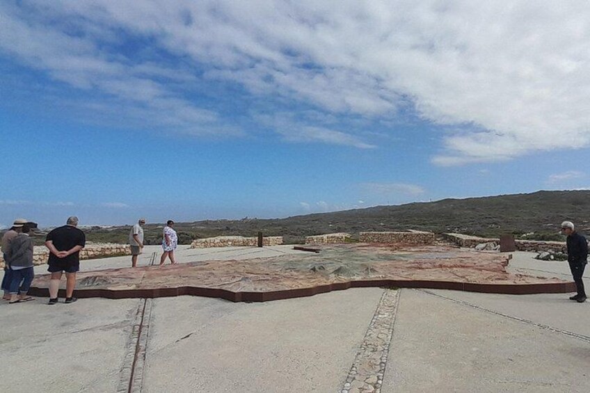 A group of people on a concrete platform overlooking a landscape with hills in the distance. 2