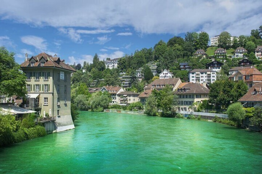 A river with a tower and houses on a hillside. 5