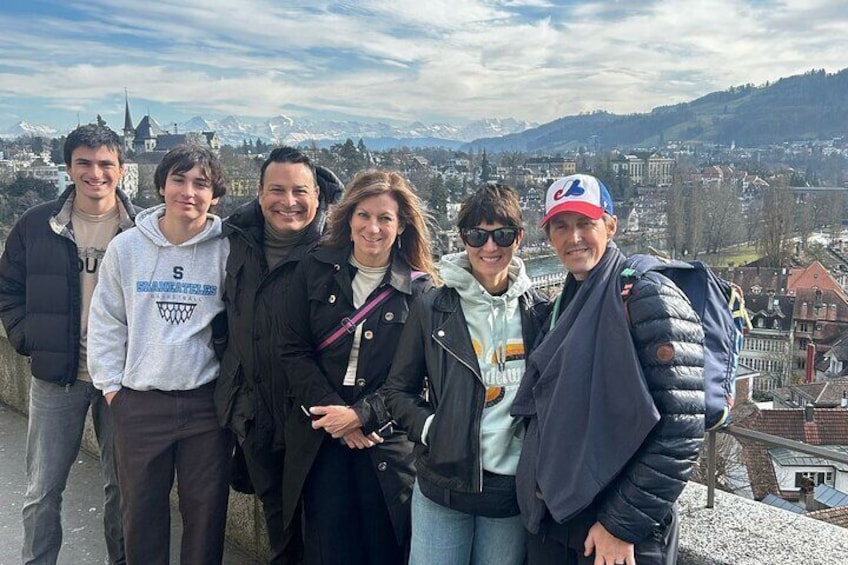 A group of people standing on a ledge with a city and mountains in the background. 1