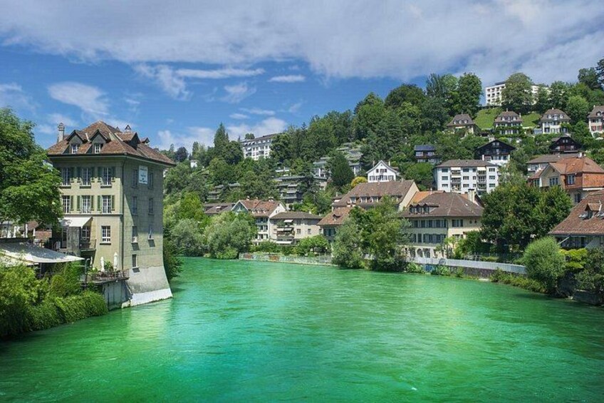 A river with a tower and houses on a hillside. 2