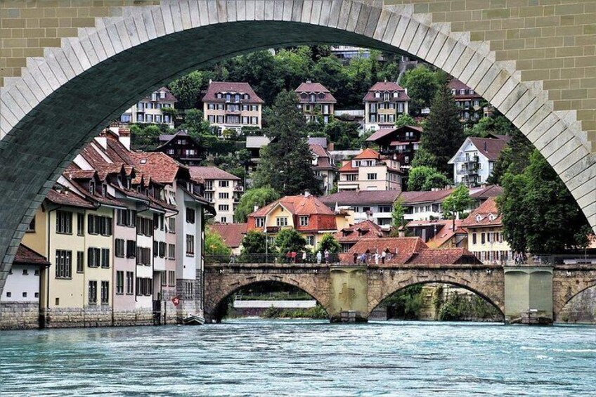 A stone bridge over a river, houses on a hillside, and a clear sky. 3