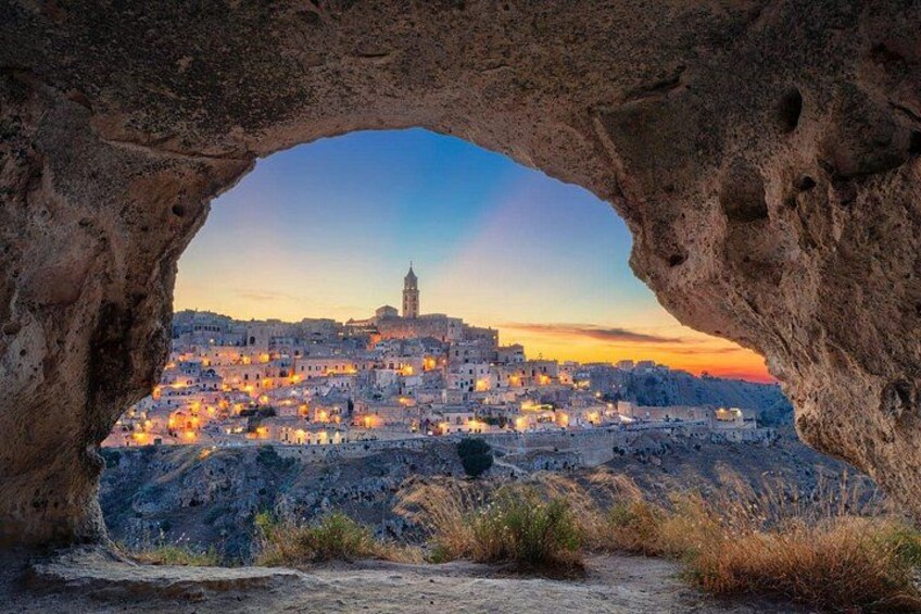 A town through a natural rock arch with a prominent tower. 5