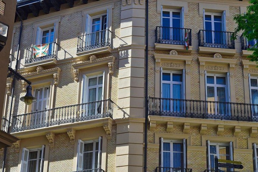 Un edificio de varios pisos con balcones, ventanas y una bandera. 4