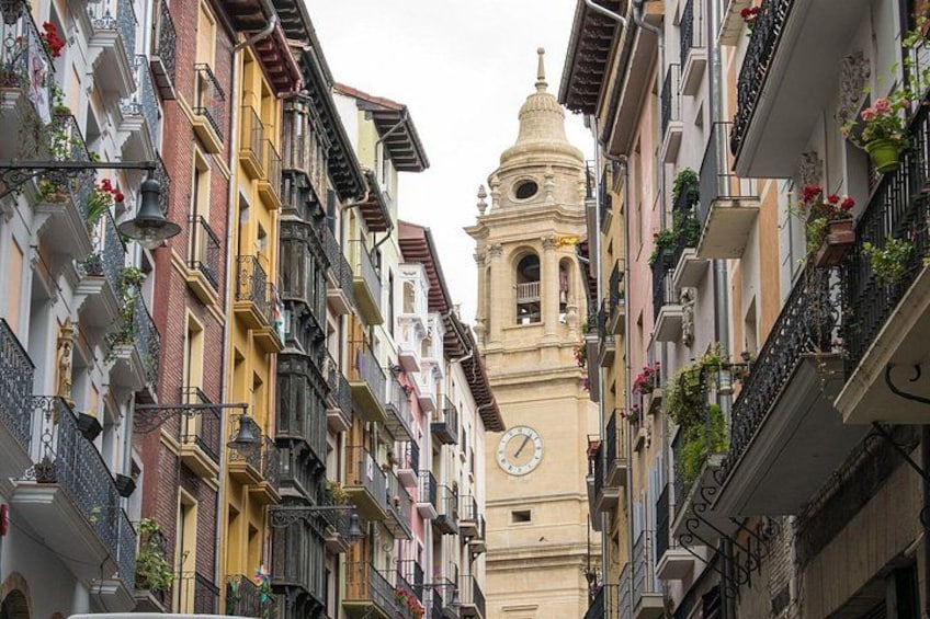 Una calle estrecha bordeada por edificios coloridos con una torre de reloj en el centro. 2