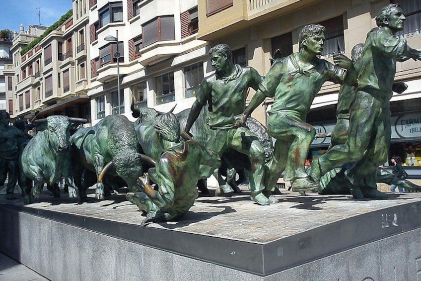 Una escultura de bronce de un toro en un entorno urbano, con edificios al fondo. 1