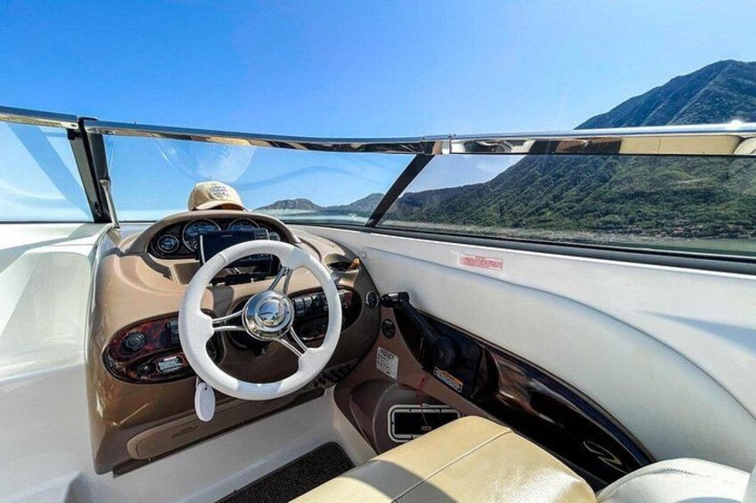 A boat's interior with a steering wheel, dashboard, and seats. 3
