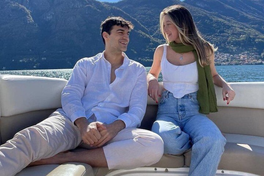 Two people sitting on a boat with a mountainous landscape in the background. 4