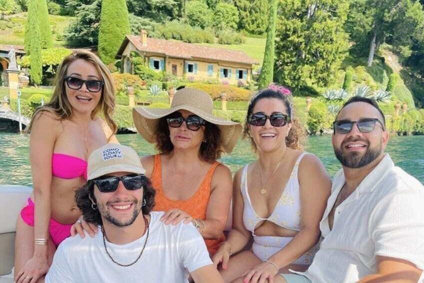 Un gruppo di persone su una barca vicino a un lago, con una casa sullo sfondo. 3