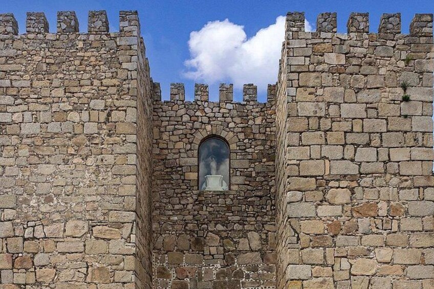 A stone castle wall with a central arched window. 3
