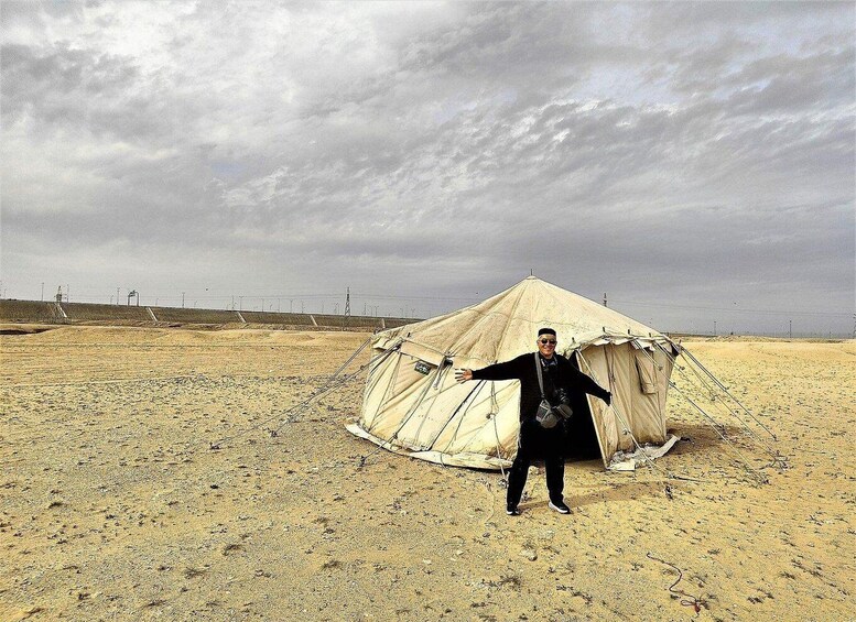 A person standing in a desert with a large tent in the background. 5