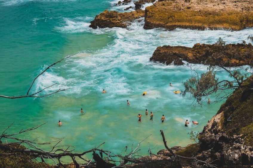 Un paysage côtier avec une eau turquoise et limpide, des affleurements rocheux et des personnes qui se baignent. 4