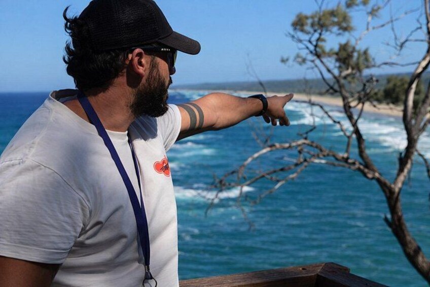 A person pointing towards the ocean from a wooden structure. 2