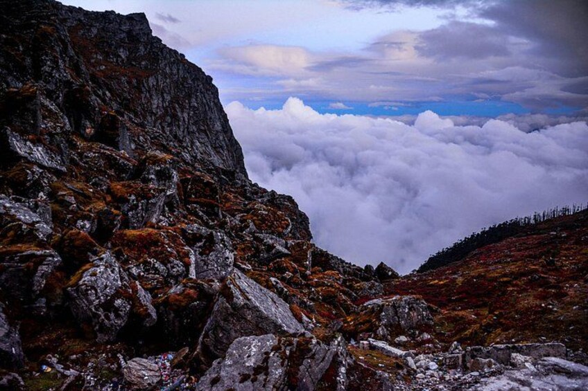 A rocky mountain landscape with a view of clouds below. 2