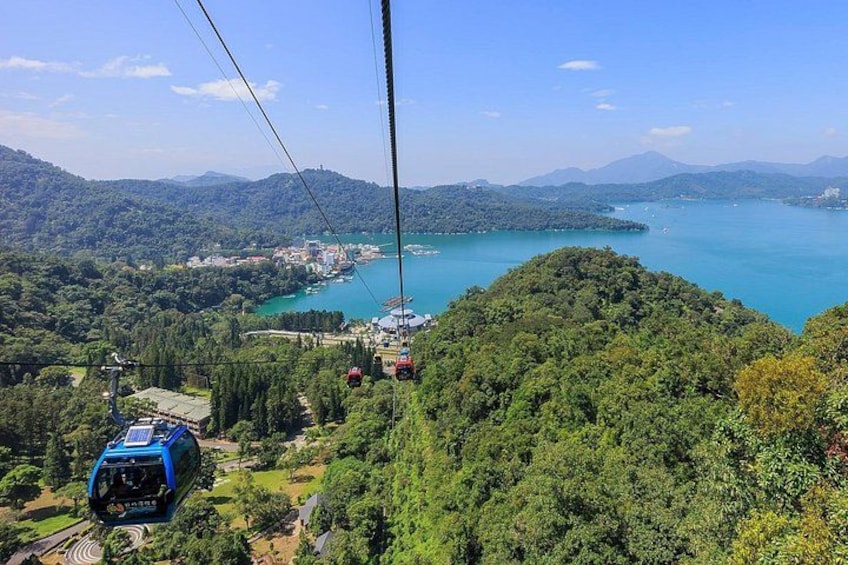A cable car system over a mountainous landscape with a lake and forested areas. 2
