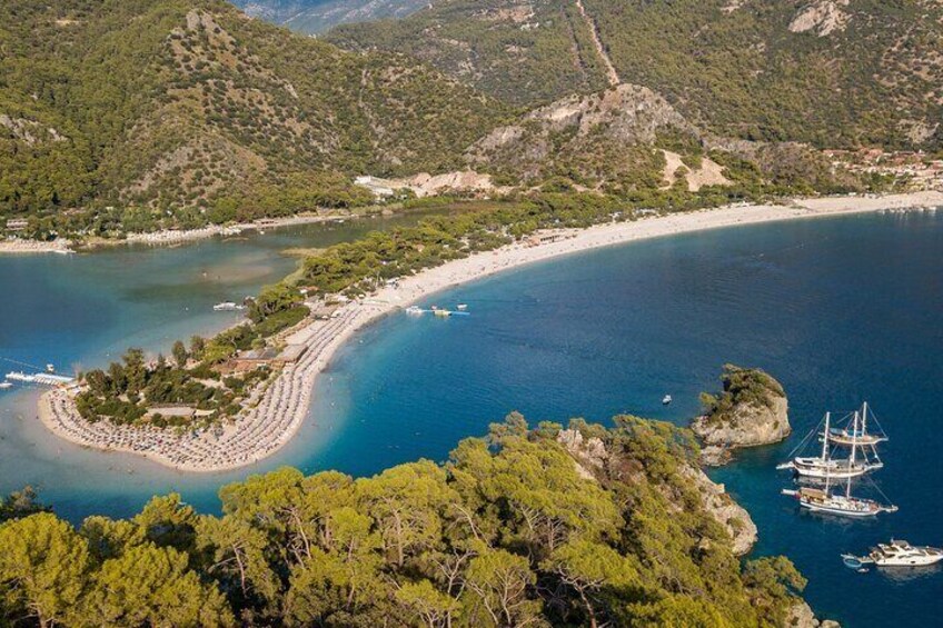 Un paisaje costero con playa, una pequeña isla y barcos en el agua. 5