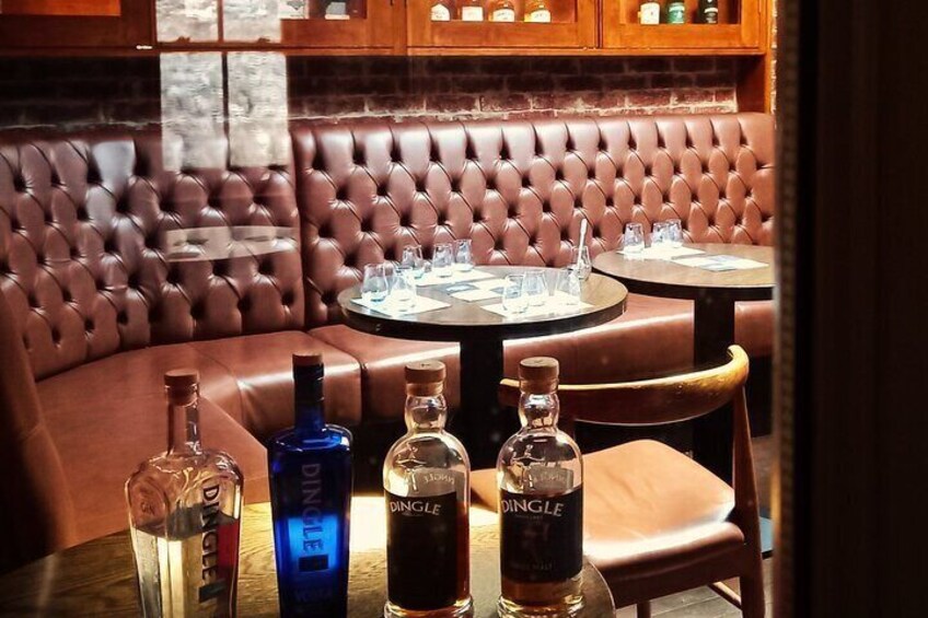 A restaurant with leather booths and tables, bottles of Dingle liquor, and glasses. 5