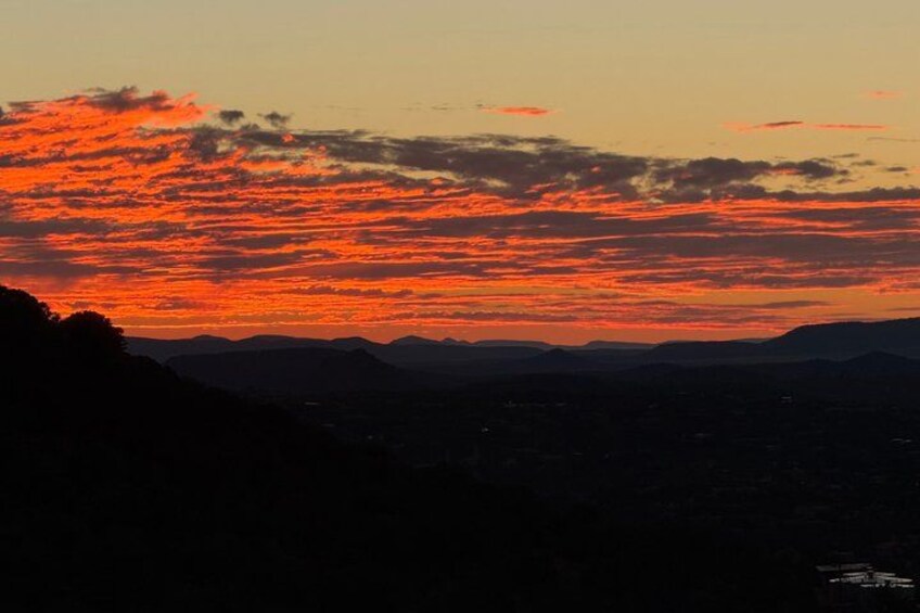 A sunset over a mountainous landscape with silhouetted hills. 2