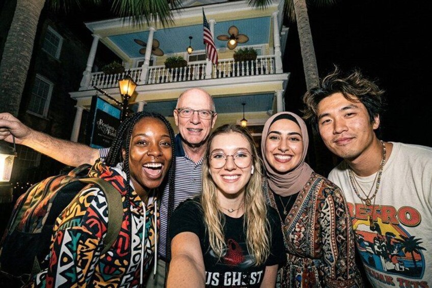 Een groep mensen poseert voor een gebouw met een balkon en een Amerikaanse vlag. 4