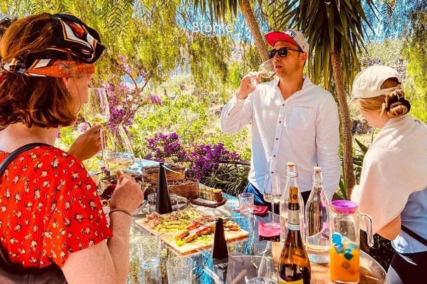 Een groep mensen geniet van een maaltijd buiten, aan een tafel gedekt met eten en drinken. 5