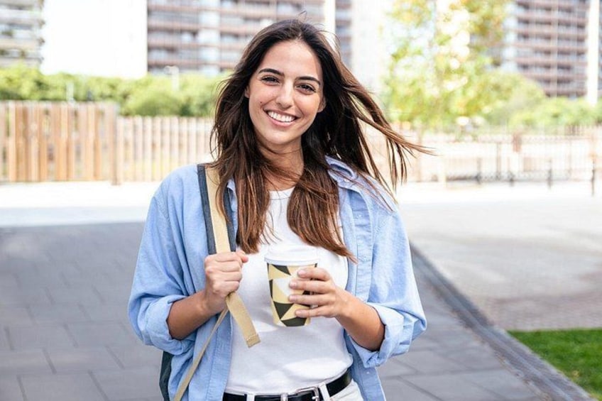 Una persona cammina all'aperto, tenendo in mano una tazza e indossando una camicia azzurra e uno zaino. 5