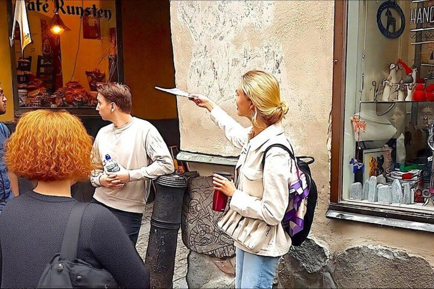 A street scene with a person pointing at a map, a shop with a sign reading 'Cafe Runsten,' and a display of handbags. 1