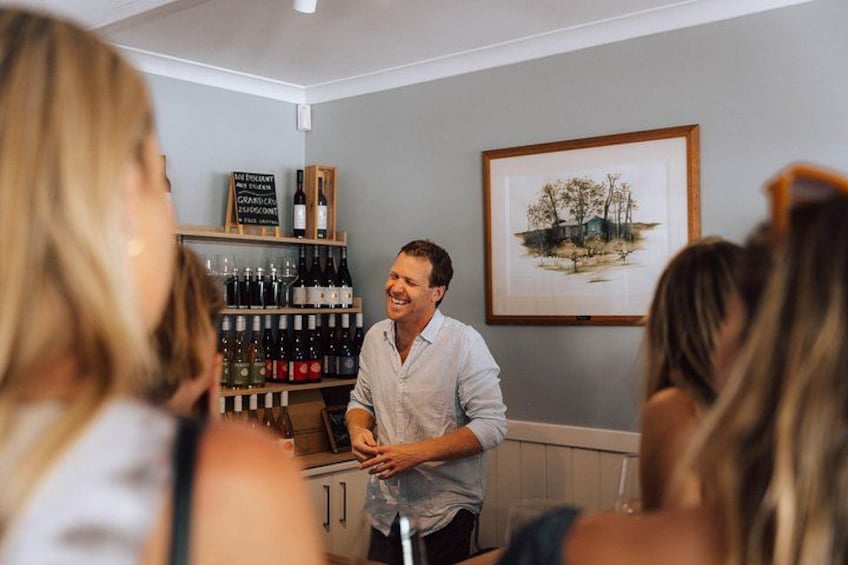Eine Person steht an einer Bar, dahinter weinengefüllte Flaschen. Im Raum hängt ein gerahmtes Bild an der Wand. 4