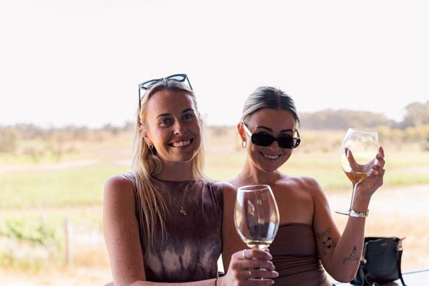 Due persone sedute a un tavolo all'aperto, con calici di vino in mano. 2