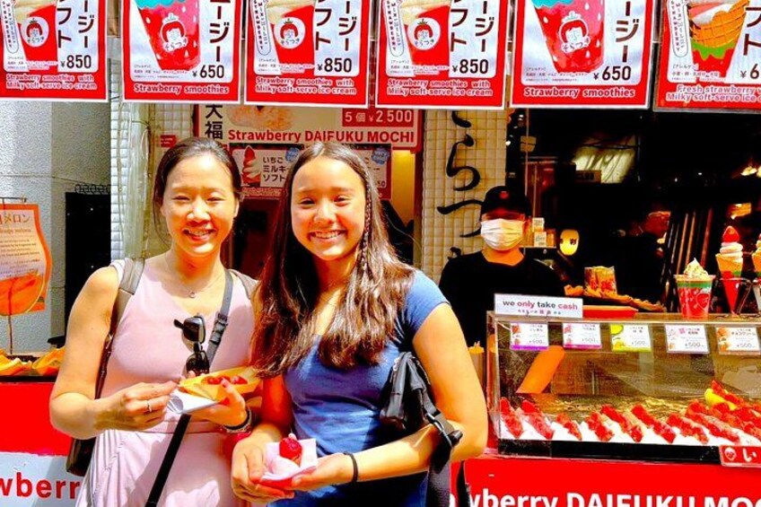 Two people holding food items at a strawberry smoothie stand. 5