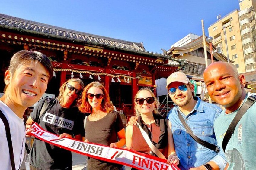 Un gruppo di persone che tiene un nastro rosso e bianco a righe con la scritta 'FINISH'. 2