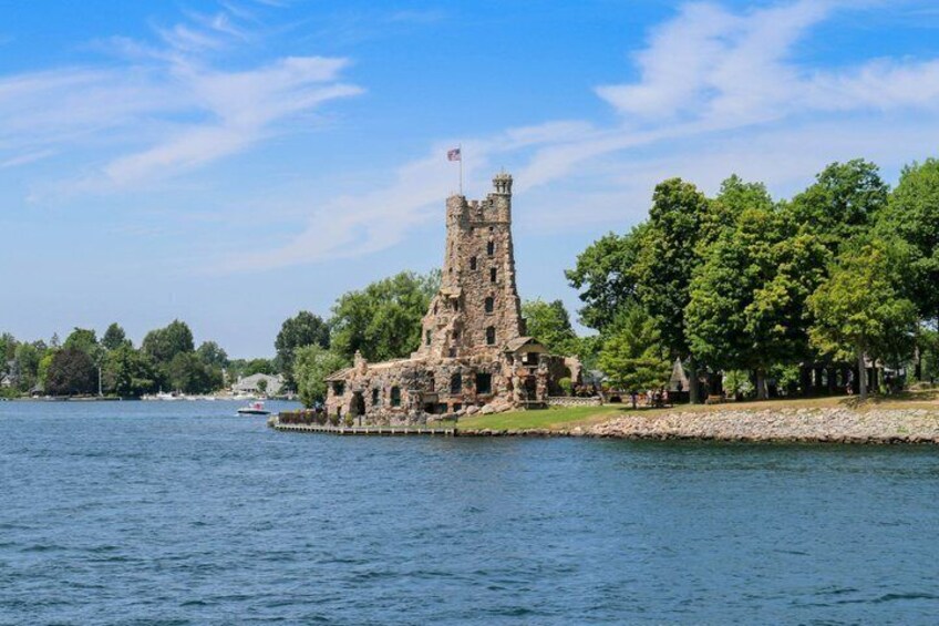 A historic stone castle by a lake with a flag on top. 5
