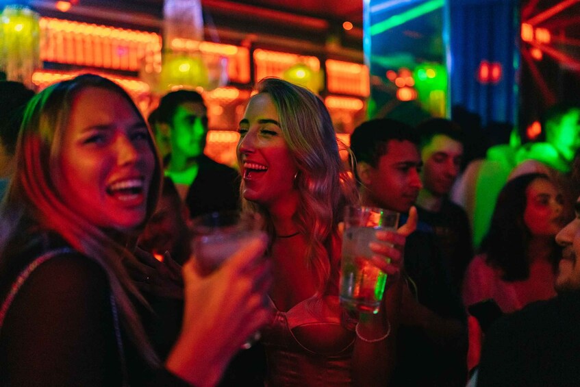 A crowded indoor setting with people holding drinks. 1