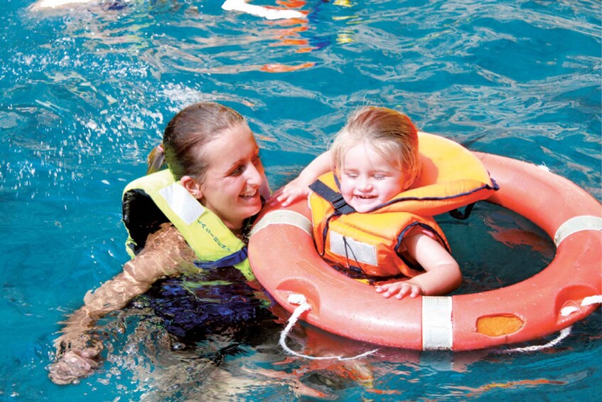 Two people in a pool with a red life ring. 2