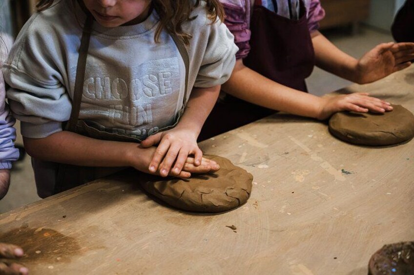 Iemand vormt klei op een houten tafel. 3