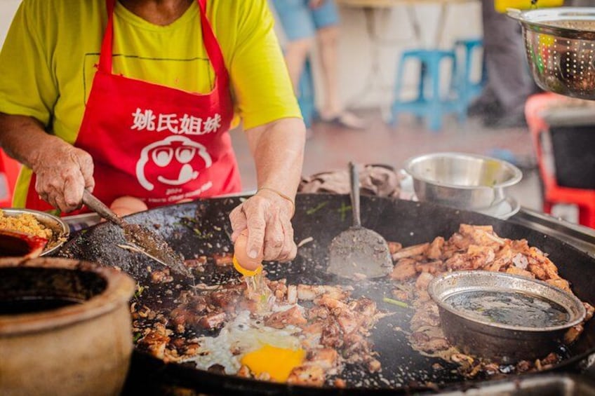 A street food vendor cooking on a large griddle with various meats and vegetables. 3