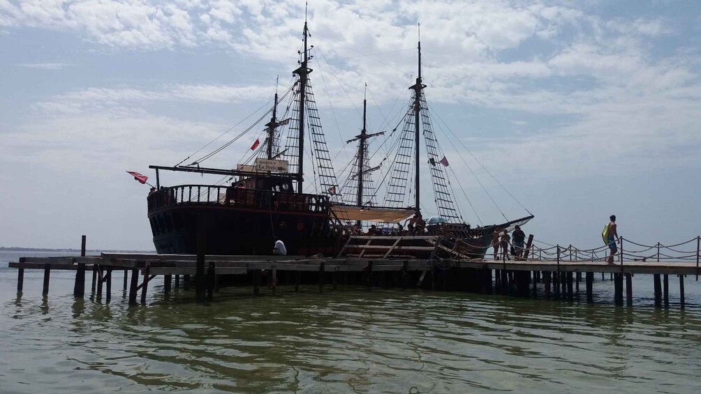 A large ship docked at a pier with people walking around it. 1