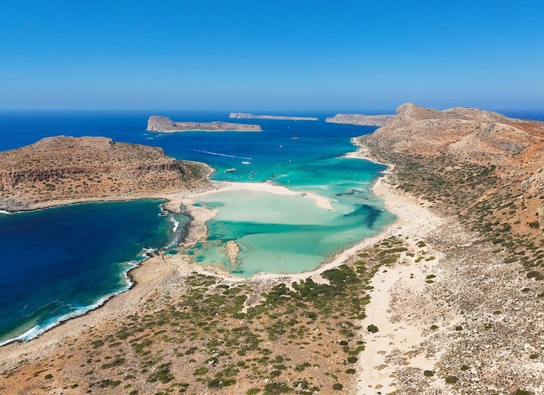 An aerial view of a coastal landscape with rocky terrain, clear turquoise waters, and a sandy beach. 5