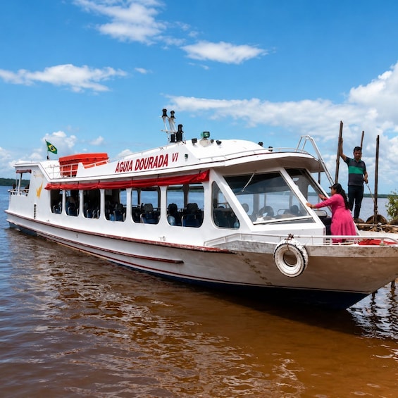A boat named 'ÁGUIA DOURADA VI' with passengers and a person standing on the deck. 3