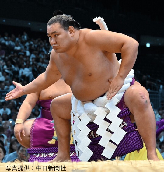 A sumo wrestler in a ring, with an audience in the background. 3