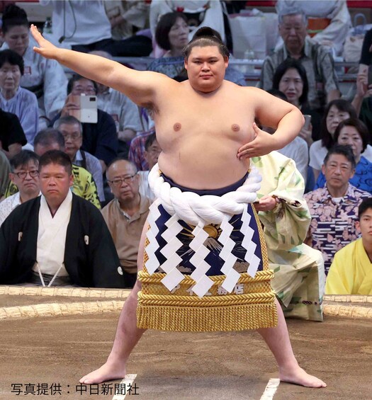 A sumo wrestler in a ring with spectators. 4