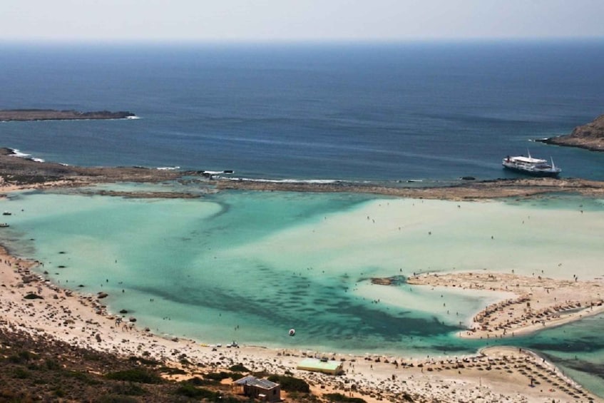 A coastal area with clear turquoise waters, a sandy beach, and a boat in the distance. 3