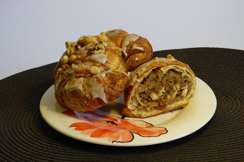 A pastry with a white icing and nuts on a plate with a floral design. 2