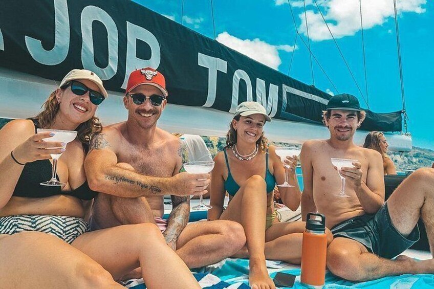 Un groupe de personnes se trouve sur un bateau à voile, tenant des boissons et une bouteille d’eau. 5