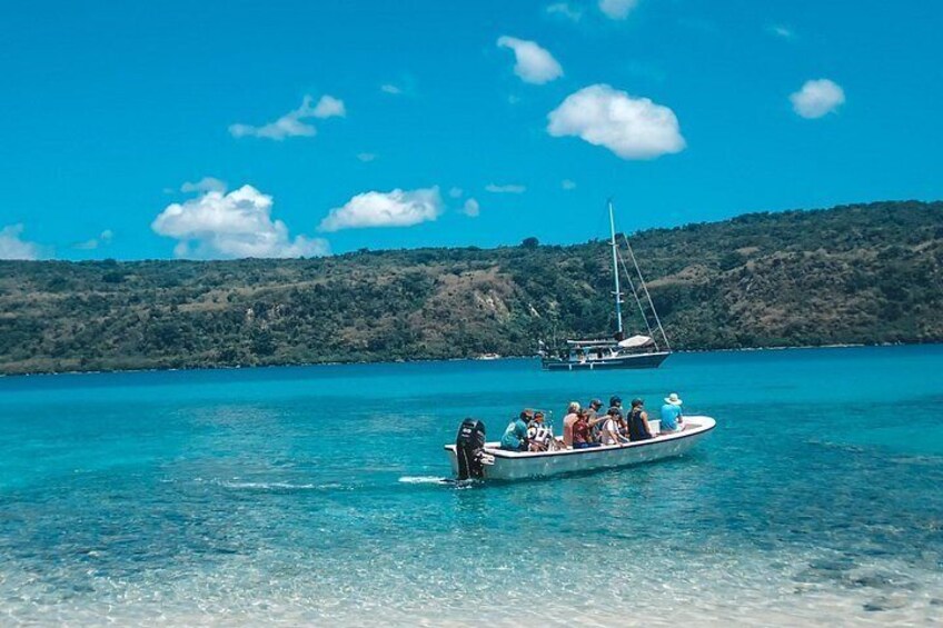 Un bateau avec des personnes à bord, sur un lac d’un bleu limpide, entouré de collines. 2