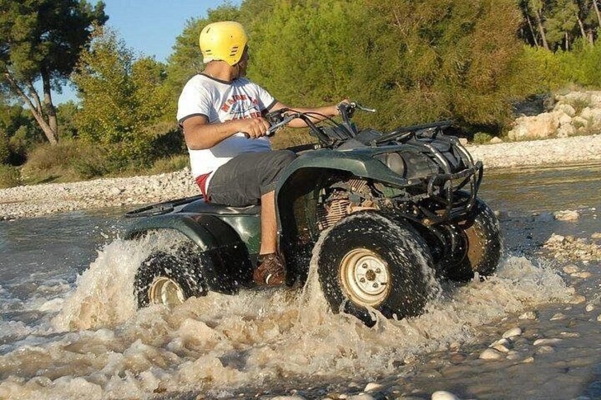 A person riding an ATV through a shallow river. 4